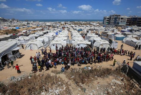 5月28日，人們在加沙城西部的沙提難民營等待領(lǐng)取救助食物。新華社發(fā)（里澤克·阿卜杜勒賈瓦德攝）